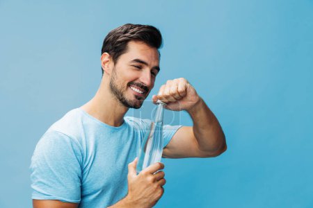 Photo for Man lifestyle bottle beauty happy water holding sexy portrait t-shirt cheerful fresh hand blue drink background smile healthy sport drinking attractive studio isolated - Royalty Free Image