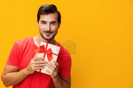 Téléchargez les photos : Homme présent tenant cadeau Noël anniversaire studio vente boîte donner modèle valentine surprise mâle célébrer fête heureux gars - en image libre de droit