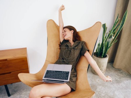 Photo for Woman sitting on a chair with a laptop at home beautiful smile and relaxation, modern stylish interior Scandinavian lifestyle, copy space. High quality photo - Royalty Free Image