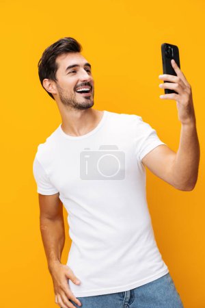 Photo for Smiling man cyberspace copy happy mobile eyeglass selfie studio business portrait communication lifestyle phone technology space surprise pointing smartphone yellow phone - Royalty Free Image