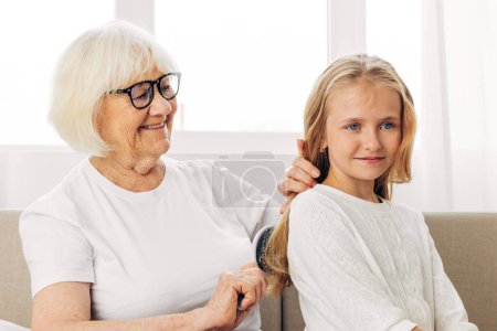 Photo for Daughter woman family senior mother combing girl love old couch sitting hug comb lifestyle sofa hair hair happy granddaughter elderly child grandmother home - Royalty Free Image