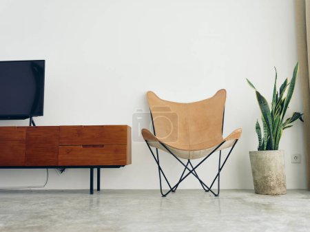 Photo for Stylish leather chair chair in a modern interior with white walls and concrete floor, wooden elements, natural daylight from the window. High quality photo - Royalty Free Image