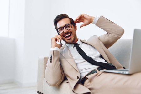 Photo for Man winner talk smile couch happy working computer glasses business office laptop telephone video manager call portrait phone attractive businessman - Royalty Free Image