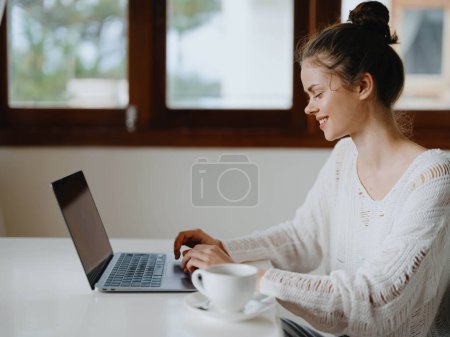 Foto de Mujer joven creativa que trabaja en un escritorio en casa en un interior acogedor con una taza de bebida, freelancer oficina en casa con una sonrisa, la comunicación y la educación en línea. Foto de alta calidad - Imagen libre de derechos
