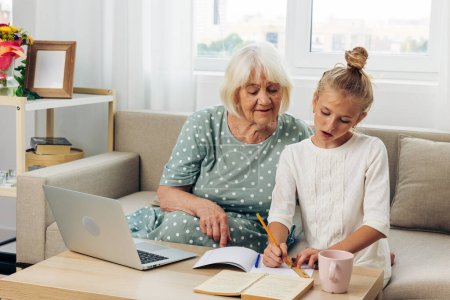 Photo for Hugging laptop t-shirt happiness granddaughter sofa grandmother togetherness photography space call smiling video people selfie copy white indoors bonding family education child two - Royalty Free Image