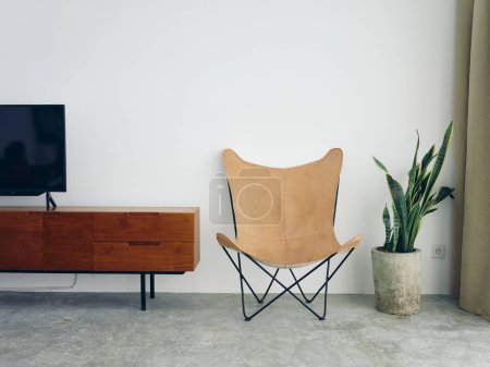 Photo for Stylish leather chair chair in a modern interior with white walls and concrete floor, wooden elements, natural daylight from the window. High quality photo - Royalty Free Image