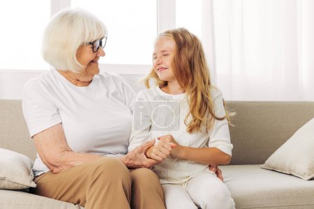 Photo for Home woman generation granddaughter lifestyle love senior couch family child indoor sitting girl happy hug grandmother old grandchild elderly sofa daughter mother joy - Royalty Free Image