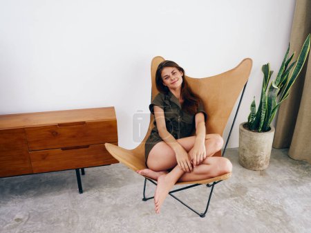 Foto de Mujer sentada en una silla en casa hermosa sonrisa, diversión y relajación, estilo moderno estilo de vida interior scandia, espacio de copia. Foto de alta calidad - Imagen libre de derechos