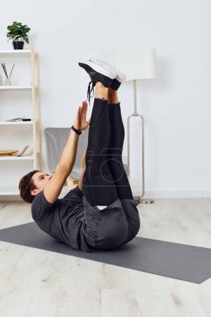 Photo for Man watch adult healthy training fitness athlete house health lifestyle indoor sportswear home sport active body activity workout mat technology gym - Royalty Free Image