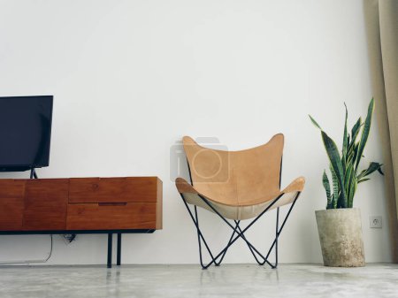 Foto de Elegante silla de cuero en un interior moderno con paredes blancas y suelo de hormigón, elementos de madera, luz natural desde la ventana. Foto de alta calidad - Imagen libre de derechos