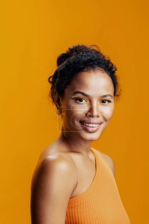Téléchargez les photos : Cosmétique femme modèle maquillage noir studio créatif coloré peau belle beauté cosmétologie sourire portrait jaune visage africain style de mode - en image libre de droit