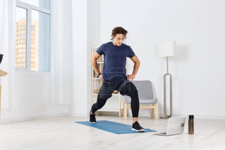 Photo for Man lifestyle house active fit living male sport indoor activity room fitness health floor mat sportswear training healthy exercise home laptop wellness - Royalty Free Image