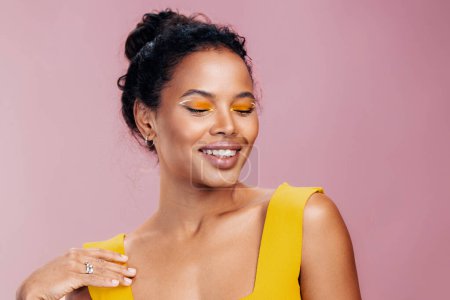 Téléchargez les photos : Africaine femme jaune style créatif copie studio coloré espace cosmétologie noir beauté peau visage cosmétique modèle portrait beau sourire mode maquillage - en image libre de droit