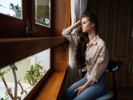 Photo for Woman fall depression sitting by the window and looking at nature, rainy weather and discouragement, home life style, loneliness. High quality photo - Royalty Free Image