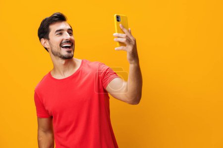 Photo for Pointing man technology smiling studio yellow lifestyle phone toothy isolated eyeglass copy smartphone surprise happy business smile mobile cyberspace message phone space communication portrait - Royalty Free Image