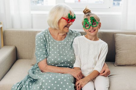Photo for Hug woman year grandparent grandchild cosy granddaughter christmas home family happy smile couch together girl love sofa glasses grandmother child holiday gift new - Royalty Free Image