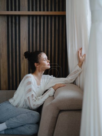 Photo for Woman in sweater and home pants relaxing lying on the couch at home, cozy day off in comfort, real lifestyle with a smile. High quality photo - Royalty Free Image
