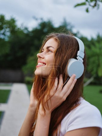 Téléchargez les photos : Portrait d'une femme portant des écouteurs sourire en gros plan avec des dents volantes cheveux. Photo de haute qualité - en image libre de droit