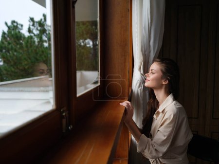 Photo for Portrait of young woman at home by window with wooden frame, autumn mood, cozy lifestyle, sleepy weather. High quality photo - Royalty Free Image