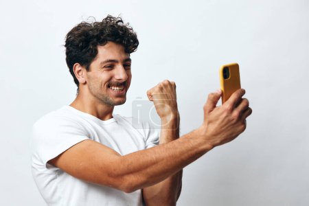 Foto de Tecnología hombre mensaje hispano usando celular caucásico en línea retrato masculino blanco pie estilo de vida camiseta casual adulto conexión teléfono hipster - Imagen libre de derechos