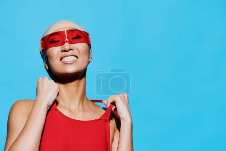 Téléchargez les photos : Asiatique femme portrait style de vie lunettes de soleil joyeuse mode beauté sourire maillot de bain style fond émotion maillot de bain rouge personne caucasien bleu dame glamour - en image libre de droit
