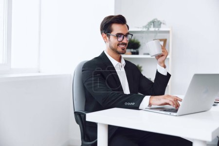 Téléchargez les photos : Homme d'affaires au bureau assis au bureau et travaillant dans l'ordinateur portable, la finance et le concept de démarrage, mode de vie de travail dans un bureau lumineux. Photo de haute qualité - en image libre de droit