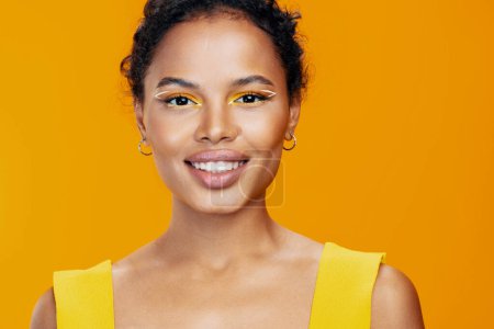 Téléchargez les photos : Mode femme style copie studio peau portrait beauté modèle cosmétologie créatif cosmétique jaune beau noir sourire visage maquillage africain espace coloré - en image libre de droit