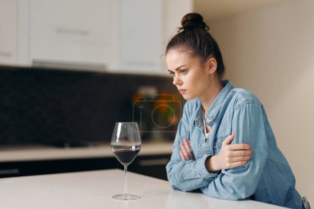 Photo for Solitude in Sorrow: A Depressed, Lonely Woman Sitting at Home, Worried and Upset, Seeking Solace in Wine - Royalty Free Image