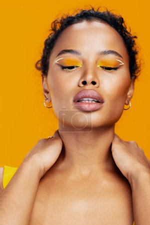 Téléchargez les photos : Mode femme oeil beauté beau maquillage africain rose modèle jaune coloré noir style espace copier studio créatif ethnique cosmétologie visage portrait heureux cosmétique sourire peau - en image libre de droit