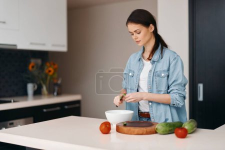 Foto de Cocina Saludable: Mujer joven cocinando ensalada vegetariana fresca en casa - Imagen libre de derechos