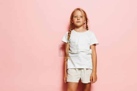 Téléchargez les photos : Charmante petite fille pose de façon décontractée sur fond de studio coloré - en image libre de droit