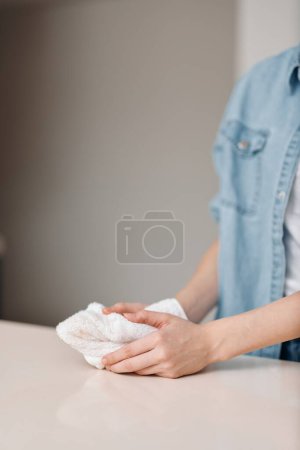 Foto de Limpio y cuidado: Una mujer limpiando las superficies del hogar con una botella de trapo y aerosol - Imagen libre de derechos