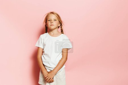 Photo for Charming Caucasian Girl in Cute Casual Attire Poses with Lovely Expression Against Pink Studio Background - Royalty Free Image