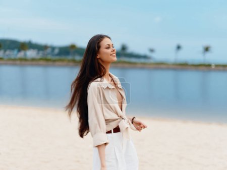 Photo for Joyful Summer Getaway: Beautiful Young Woman Walking Alone on a White Sandy Beach, Enjoying the Warmth of the Sun and Cool Breeze of the Azure Ocean - Royalty Free Image