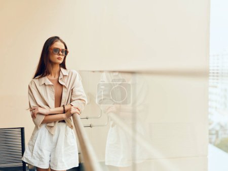 Foto de Mujer de negocios caucásica pensativa, joven y con estilo, de pie en un estudio moderno con un fondo de pared de moda - Imagen libre de derechos