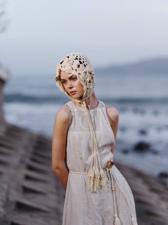 Téléchargez les photos : Beauté sereine : Une jeune femme dans une robe d'été élégante, posant sur un fond de plage de sable blanc et de vagues d'océan cristallines - en image libre de droit