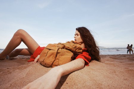 Téléchargez les photos : Délice des voyageurs : Joyeuse femme Backpacker dans la nature, se détendre sur une belle plage au bord de la mer avec vue grand angle - en image libre de droit