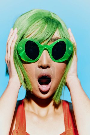 Téléchargez les photos : Femme sourire style rétro portrait lèvres choqué été vert tendance beauté maillot de bain lunettes de soleil élégant jeune perruque rouge main joie bouche cheveux - en image libre de droit
