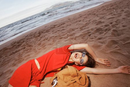 Téléchargez les photos : Joie de Voyage : Une femme ivre sur la plage, sable entre ses orteils, détente dans les natures Aventure Vacances - en image libre de droit