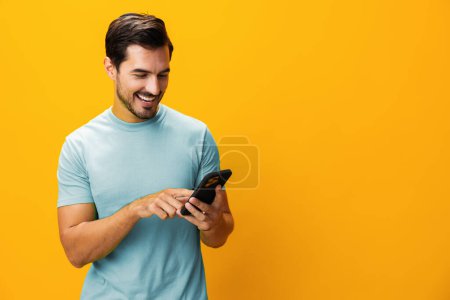 Foto de Hombre gafas estilo de vida apuntando mensaje de comunicación feliz negocio móvil sorpresa retrato teléfono sonriendo ciberespacio teléfono espacio smartphone estudio amarillo tecnología copia - Imagen libre de derechos