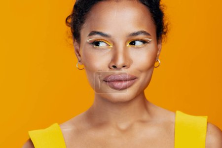 Foto de Mujer ojo belleza cosmética amarillo negro modelo creativo copia africana hermoso estudio estilo colorido sonrisa rosa moda maquillaje cara espacio cosmetología retrato piel étnica - Imagen libre de derechos