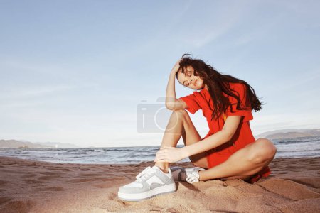 Téléchargez les photos : Femme insouciante, souriant sur une plage ensoleillée - Intégrer bonheur et liberté dans une tenue de mode à la mode - en image libre de droit