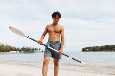 Téléchargez les photos : Homme asiatique actif jouissant de plaisir été SUPboarding aventure sur la plage - en image libre de droit