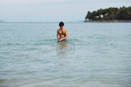 Photo for Active Asian Man Enjoying Tropical Vacation by Swimming in the Beautiful Blue Ocean - Royalty Free Image