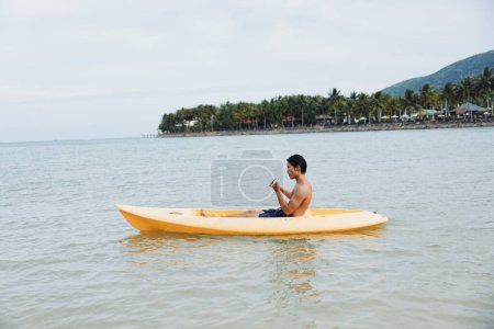 Photo for Joyful Asian Man on a Kayak, Enjoying a Tropical Beach Vacation - Royalty Free Image