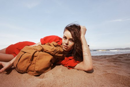 Téléchargez les photos : Joyful Traveler : Une femme routards embrassant la sérénité de la nature sur une belle plage au bord de la mer - en image libre de droit