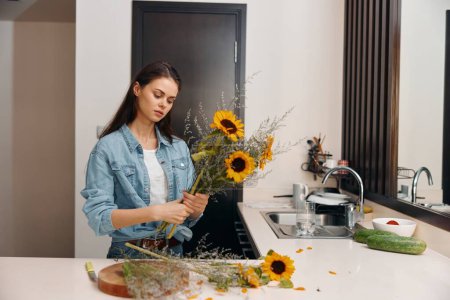 Téléchargez les photos : Femme jeune femme au foyer, attrayant et heureux, tenant des légumes frais dans la cuisine - en image libre de droit