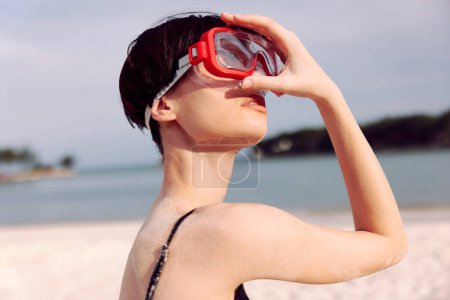Foto de Mujer alegre en traje de baño rojo, sonriendo con snorkel y máscara, disfrutando de vacaciones tropicales en Sandy Beach - Imagen libre de derechos