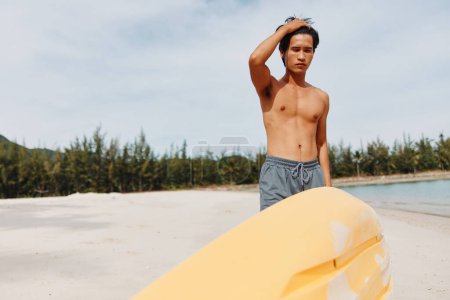 Téléchargez les photos : Happy Asian Man Kayak sur une plage tropicale : Aventure exaltante dans le paradis ensoleillé - en image libre de droit