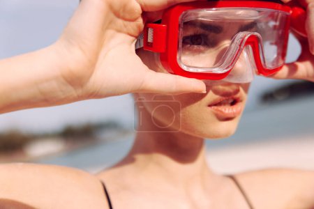 Photo for Cheerful Woman Enjoying Tropical Vacation: Smiling in Red Snorkeling Mask and Swimsuit against Blue Ocean Background - Royalty Free Image